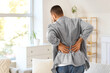 © Pixel-Shot - Young man suffering from back pain at home