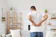 © Pixel-Shot - Young man suffering from back pain at home
