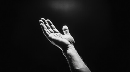 monochrome image of outstretched male caucasian adult hand against dark background