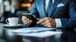 © M_H_L - Businessman using phone reviewing documents at cafe