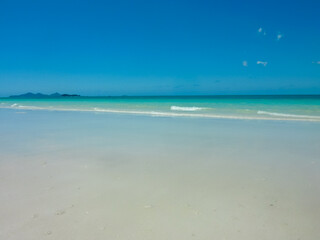 Wall Mural - Pristine white sandy beach stretches along turquoise waters at Whitehaven Beach, Whitsunday Islands, Queensland, Australia. Gentle waves meet powdery silica sand. Vibrant blue sky. Summer vacation