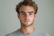 © marimalina - Young man with short, curly hair poses in front of a neutral background, showcasing an expression of calm confidence during a studio shoot