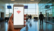 © Alina - Hand holding smartphone displaying Public Wi-Fi selection in blurred airport terminal