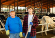 © JackF - Elderly and youth men farm workers standing in cowhouse.