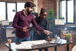 © DC Studio - African american expectant mother and coworker review financial strategy details on digital devices, collaborating in multicultural workspace. Diverse team having professional meeting at office desk.