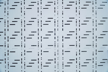 Poster - Close-up view of a repeating geometric pattern on a white metal gate surface. The design features short, parallel lines creating a unique texture. Abstract Geometric Pattern on Light Metal Surface