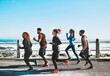 © peopleimages.com - Fitness, health and people running by beach for race, marathon or workout training together. Sports, activity and group of athletes with cardio exercise for wellness outdoor by ocean in morning.