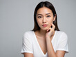 © riddler - Portrait of a young Asian woman with a thoughtful expression against plain background