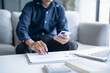 © Charlie's - Man calculate finances home pay bills taxes on mobile phone and calculator financial at home