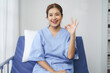 © Crystal - Smiling patient showing ok sign while sitting on hospital bed