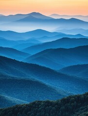 Wall Mural - blue mountain layers at sunset with soft orange sky and hazy atmosphere in a scenic landscape