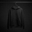 © SIdiq - A plain black hoodie hanging on a sleek metal hanger against a dark gray background, subtle shadows, and a matte finish.