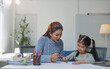 © Phimwilai - Mother and her young daughter enjoy a creative drawing session at home. The child focuses on her artwork while the mother guides her, fostering learning and creativity in a cozy environment