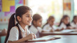 © UniqGraphicX - Indian female student writing on notebook sitting in a modern classroom.