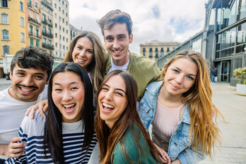 Portrait of young group of millennial generation friends smiling at camera standing together at city street