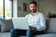 © Premium Illustration - Confident bearded man in white shirt working on laptop sitting on gray sofa in modern living room with natural light and green plants for remote work, business, technology, home office, productivity