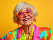 © sam - studio portrait of happy senior retired woman wearing colourful clothes, isolated on yellow background