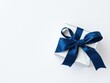 © Prasert - Simple yet sophisticated silver gift container adorned with a navy blue bow on a light gray surface, gray background, decorative gift