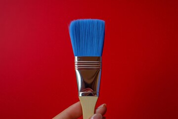 Leinwandbilder - Bright blue paintbrush held against a vibrant red background showcasing creativity in art
