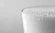 © Maryanto - Close-up of frothy milk in glass, condensation, light background, dairy product
