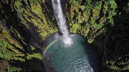 Aufkleber - Majestic waterfall cascading into serene pool surrounded by lush greenery in a remote location