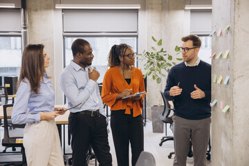 Wall Mural - Group of diverse business people discussing new ideas using sticky notes during a productive meeting in a modern office environment