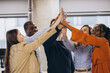 © anatoliycherkas - Diverse business team connecting hands, expressing unity and achievement in contemporary workplace environment