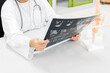 © arcyto - Doctor holding patient bone x-ray film before surgery.Image MRI and CT scan at radiology orthopedic department in hospital.Knee join xray for treatment.Physiotherapy teach model for injured athlete.