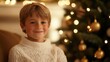 © The 2R Artificiality - Happy boy in a cozy white sweater smiling near a beautifully decorated Christmas tree glowing with lights and ornaments.