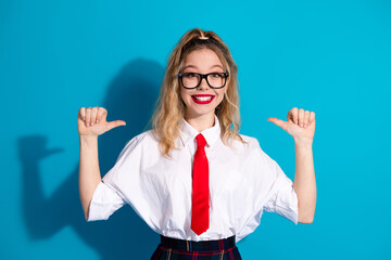 Wall Mural - Smiling young woman in school uniform with a vibrant blue photoshoot studio background showcasing youthful energy and fashion.