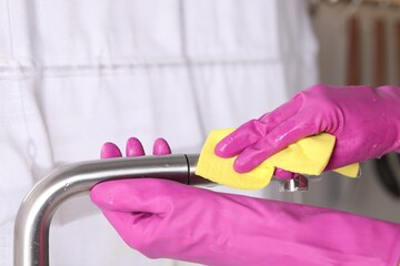 Wall Mural - Woman cleaning faucet of kitchen sink with rag indoors, closeup