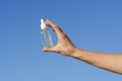 © Daryna  - Female hand holding a transparent glass jar of serum with a pipette dispenser on a blue sky background. Concept of beauty and aesthetics products, facial skin care
