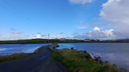 Wall Mural - Island Roy in Donegal A stunning and picturesque coastal road that gracefully winds through serene waters beneath a bright blue sky