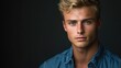© The 2R Artificiality - Contemporary portrait of young 20-year-old Caucasian man with blonde hair and blue eyes wearing denim shirt against dark background