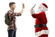 © Ljupco Smokovski - Male student making high-five gesture with Santa Claus