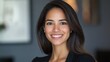 © The 2R Artificiality - Professional headshot of confident young Hispanic businesswoman smiling brightly in corporate office environment with soft lighting and modern decor.