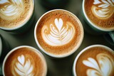 Four ceramic cups with artistic designs made from steamed milk and espresso
