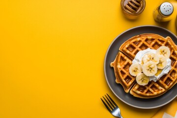 Aufkleber - Golden waffles are adorned with whipped cream, banana slices, and honey, set against a vibrant yellow background with a fork partially visible