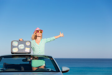 Wall Mural - Happy young woman with retro suitcase travel by car by the sea