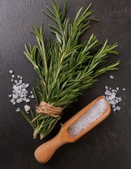 Wall Mural - Fresh rosemary sprigs and a scoop of sea salt on a dark surface. Rustic and elegant.