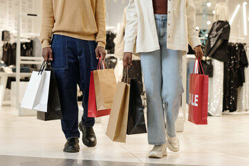 Wall Mural - Cropped shot of young African American couple in casual apparel carrying paperbags with bought items after shopping