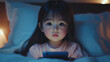 © Infinity Lens - Closeup of a little girl scrolling on her phone or tablet screen in the evening or night. young female toddler child technology and social media addiction, surfing on an electronic device in her room.