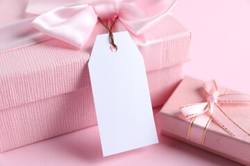 Wall Mural - Gift boxes with blank tag on light pink background, closeup