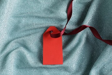 Wall Mural - Blank tag with ribbon on teal fabric, top view