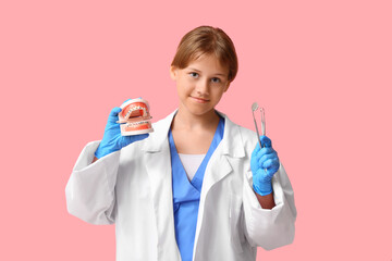 Poster - Portrait of teenage dentist with dental tools and jaw model on pink background