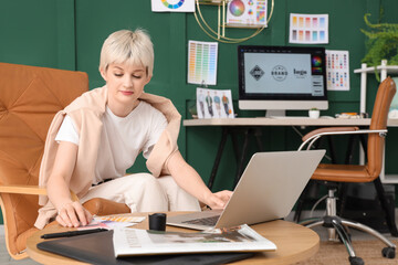 Poster - Young female graphic designer working with laptop on table in office