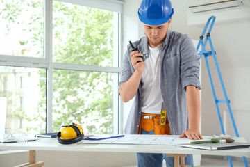 Wall Mural - male contractor with house plan talking on radio transmitter in room