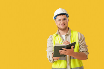Wall Mural - male contractor writing in notebook on yellow background