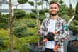 © Serhii - Gardener at work near sprouts of bushes and trees. Horticulture and sale of trees