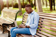© Prostock-studio - Portrait of cool black guy using laptop on bench at park, working remotely, communicating on webcam. Funky young student participating in online class or web conference outdoors